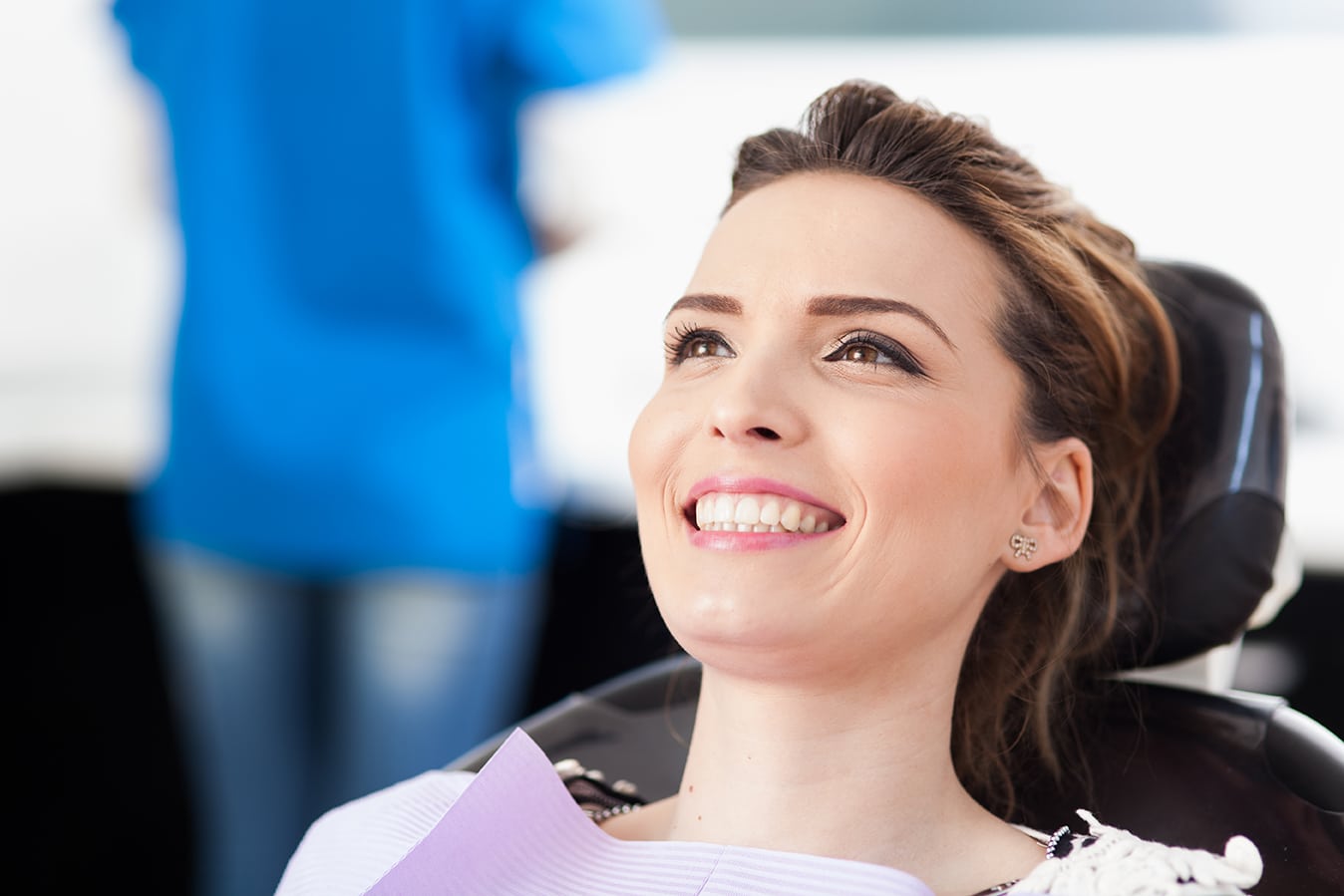 Closeup of a woman patient at the dentist waiting to be checked up with the woman doctor in the background