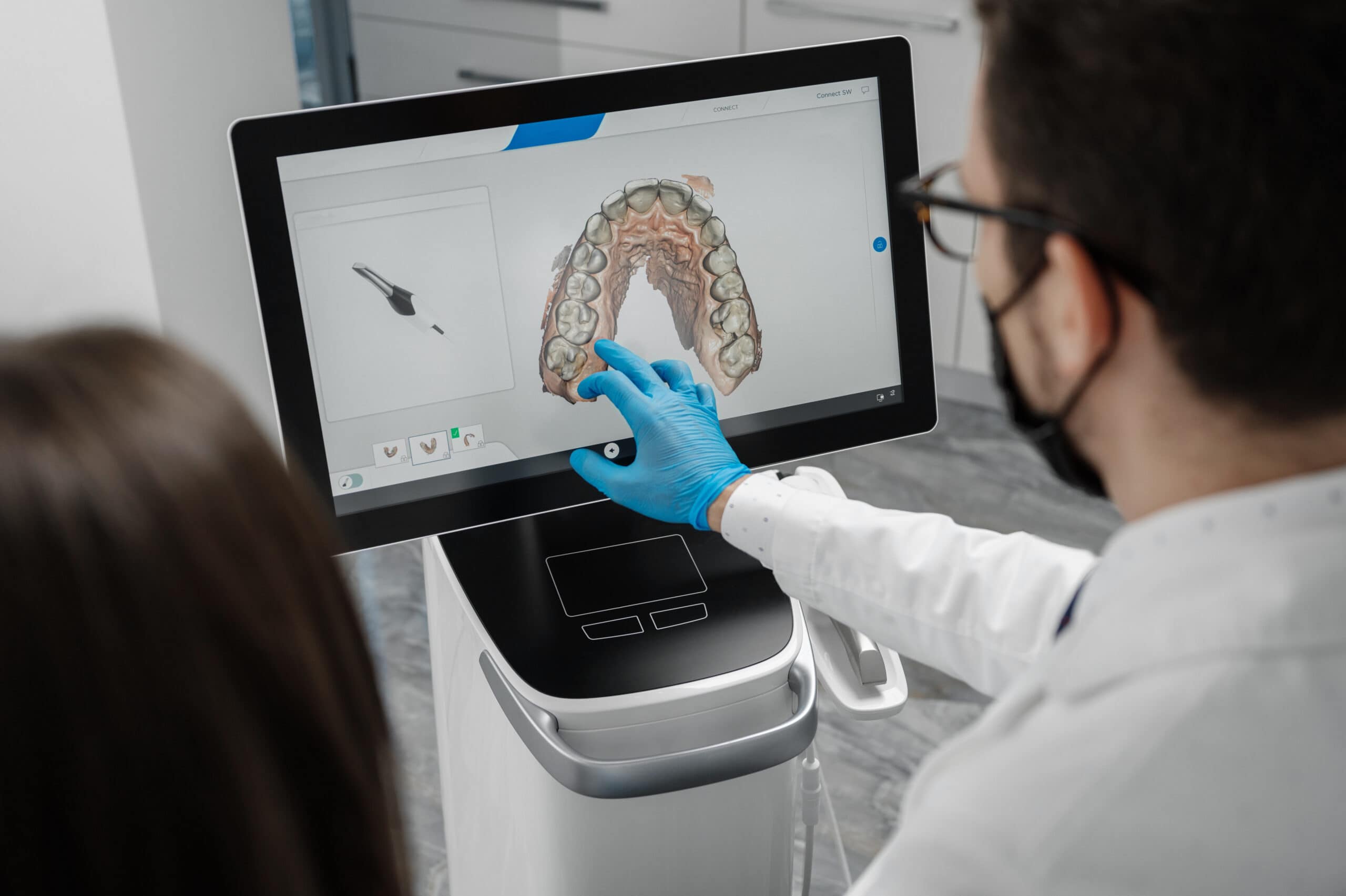 Male doctor show results of digital intraoral scan of patient teeth in 3D on display. Dentist point finger on screen